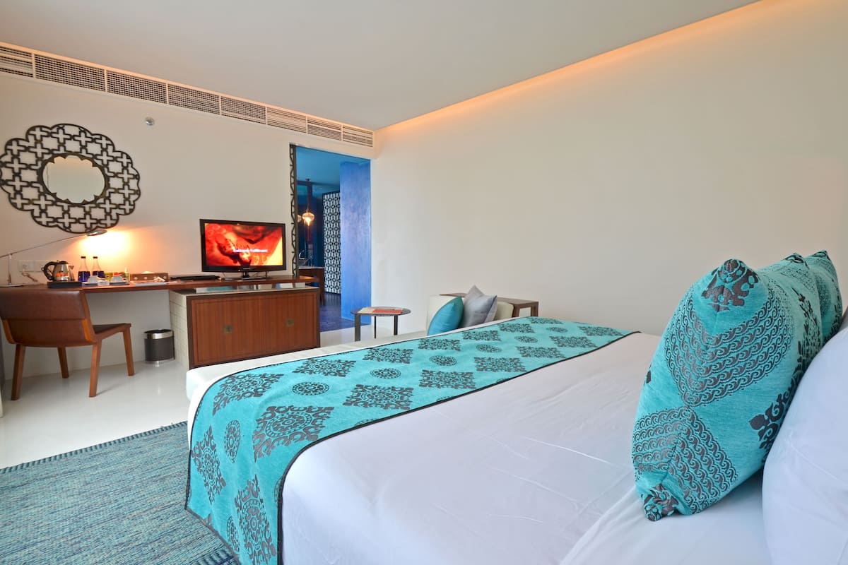 Une chambre d’hôtel avec un lit, un bureau, une télévision et une vue sur l’extérieur.