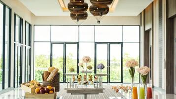 A modern interior with large windows, a dining area with a buffet, and a bar with drinks.