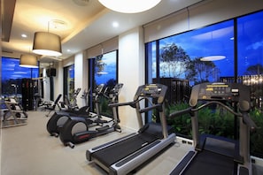 Un gimnasio con cintas de correr, elípticas y equipo de pesas.