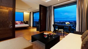 A modern hotel room with a large balcony, a bed, a dining table with a vase of flowers, and a view of the cityscape. - Avani Khon Kaen Hotel & Convention Centre (Khon Kaen)