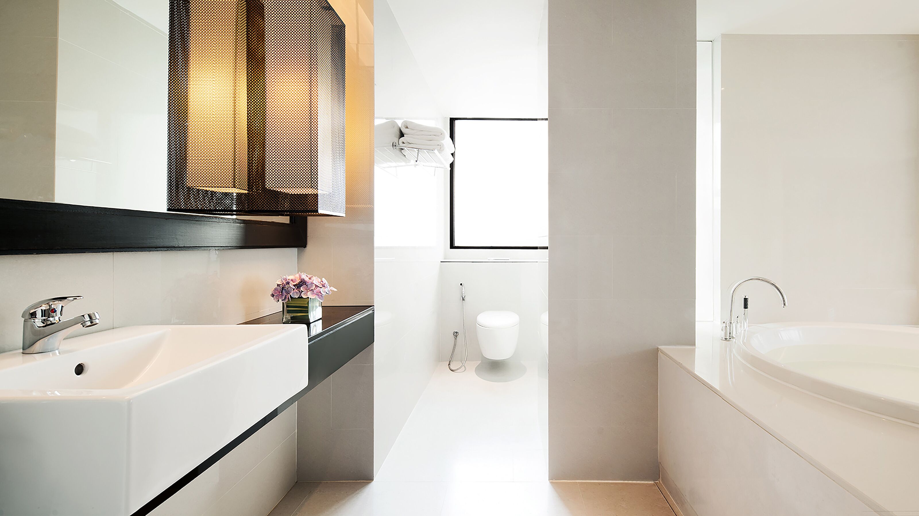 A modern bathroom with a large mirror, two sinks, a bathtub, and a toilet.