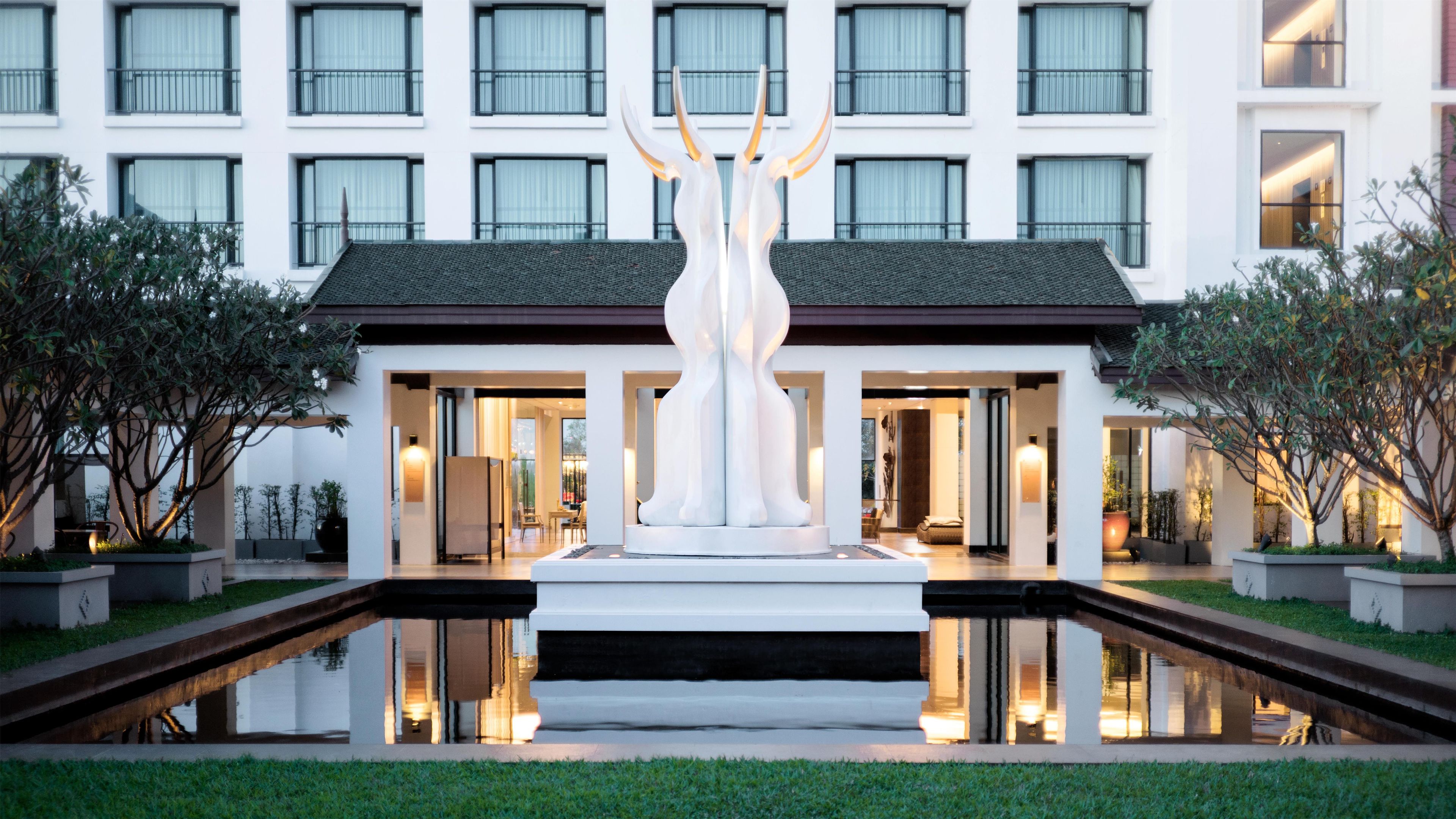 A modern hotel with a central water feature and a symmetrical facade.
