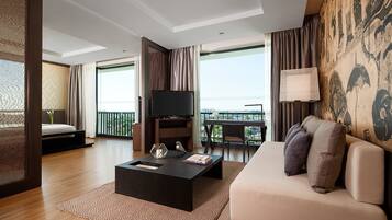 A modern hotel room with a sofa, a coffee table, a TV, and a balcony with a view.