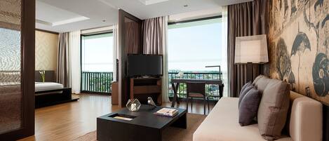 Habitación de hotel moderna con sofá, mesa de centro, televisor y balcón con vistas.