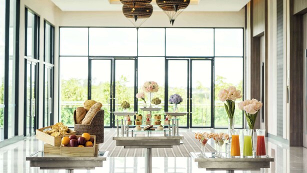 A modern dining area with a buffet setup, large windows, and decorative lighting. - Avani Khon Kaen Hotel & Convention Centre (Khon Kaen)