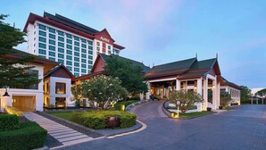 A hotel with a modern design, featuring a large building with a red roof and multiple windows. There is a well-maintained garden area with pathways and greenery. - Avani Khon Kaen Hotel & Convention Centre (Khon Kaen)