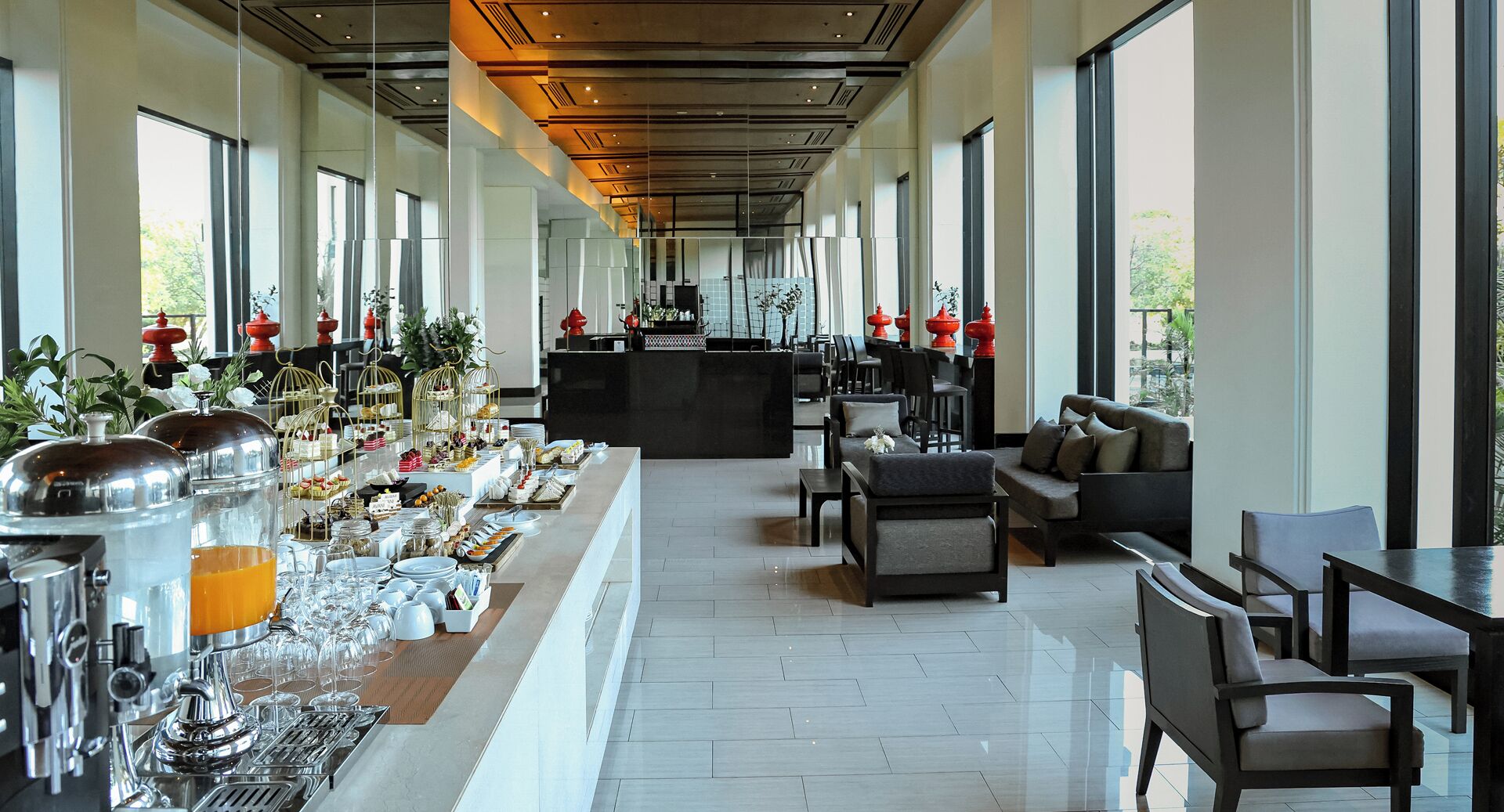 Un hall d’hôtel spacieux, doté d’un long comptoir d’accueil, d’un espace salon et de grandes fenêtres offrant une vue sur l’extérieur.
