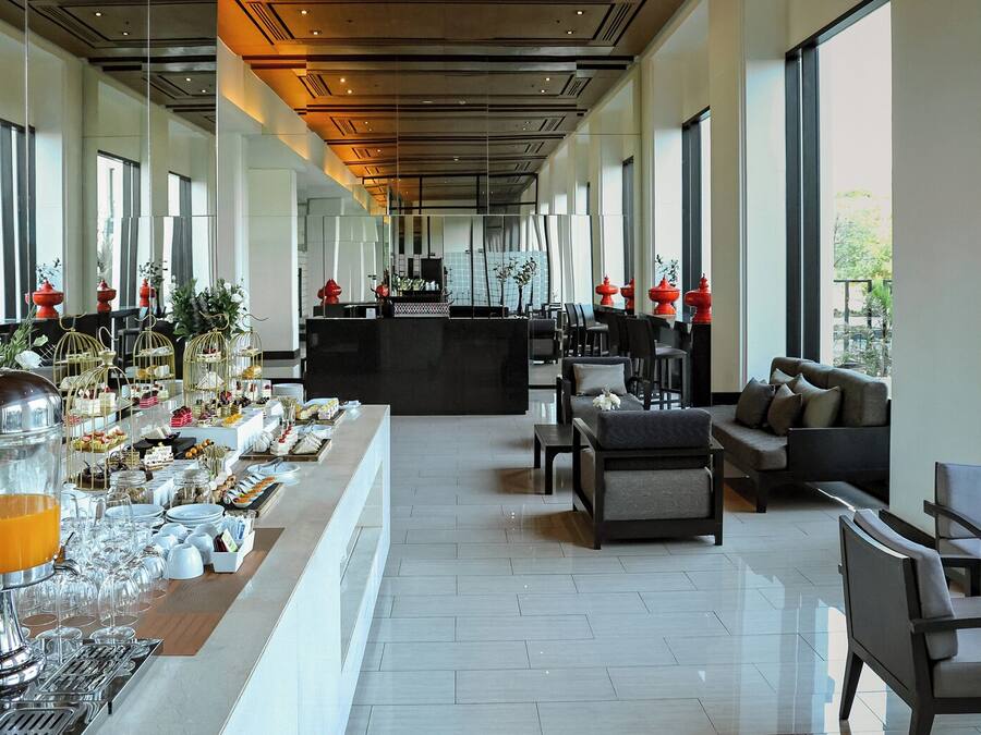 Un hall d’hôtel spacieux, doté d’un long comptoir d’accueil, d’un espace salon et de grandes fenêtres offrant une vue sur l’extérieur.