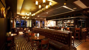 A bar area with a checkered floor, leather booth seating, and a bar counter with various bottles. - Avani Khon Kaen Hotel & Convention Centre (Khon Kaen)