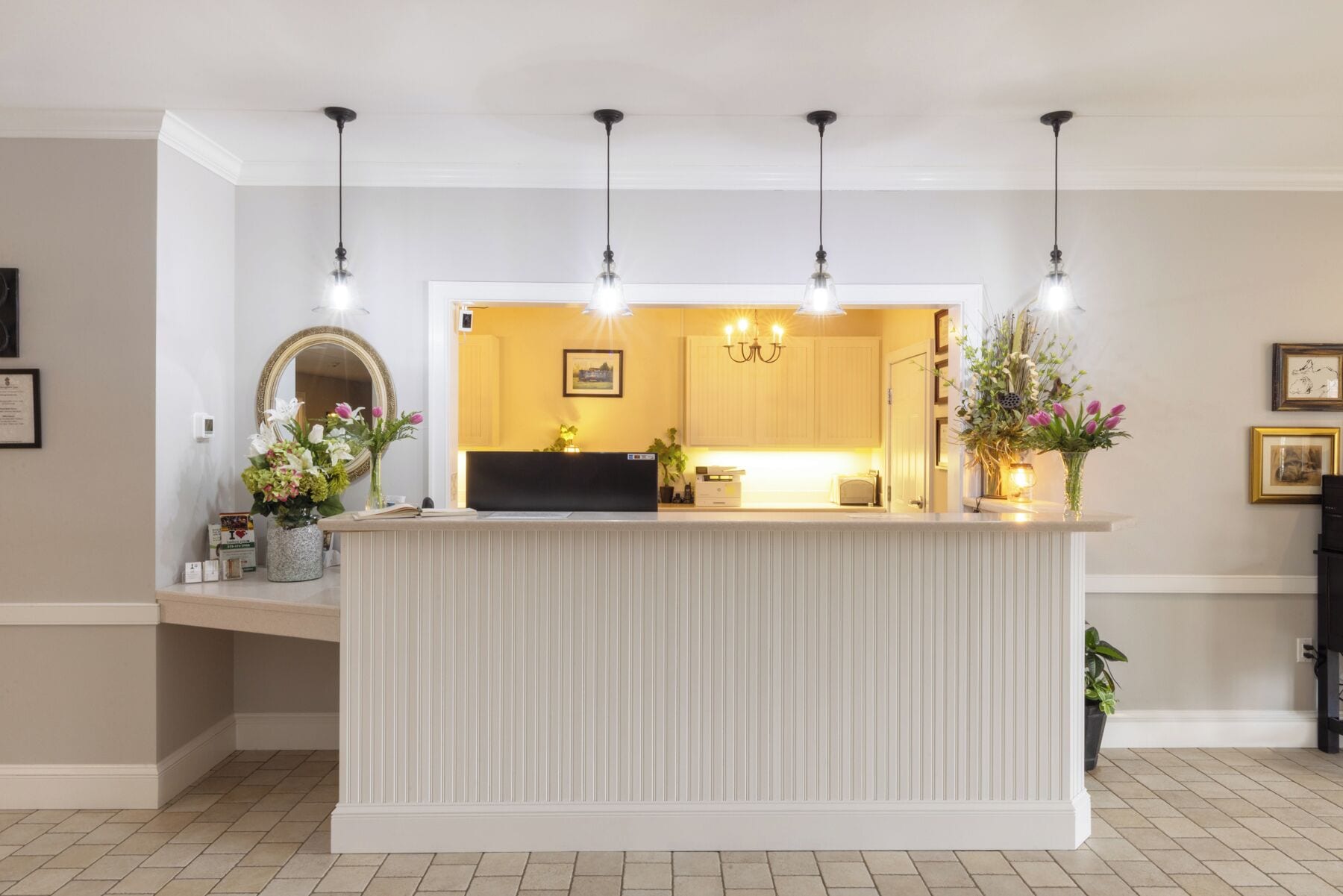 A reception area with a counter, a mirror, and a chandelier.