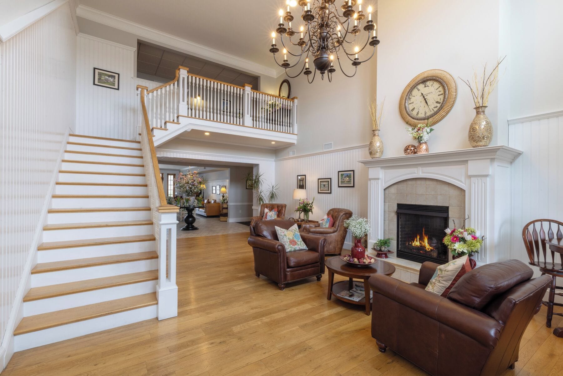 A spacious living room with a fireplace, leather sofas, and a staircase leading to an upper level.
