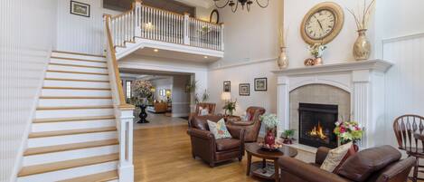 A spacious living room with a fireplace, leather sofas, and a staircase leading to an upper level.