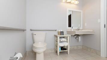 A bathroom with a toilet, a sink, a mirror, and a towel rack.