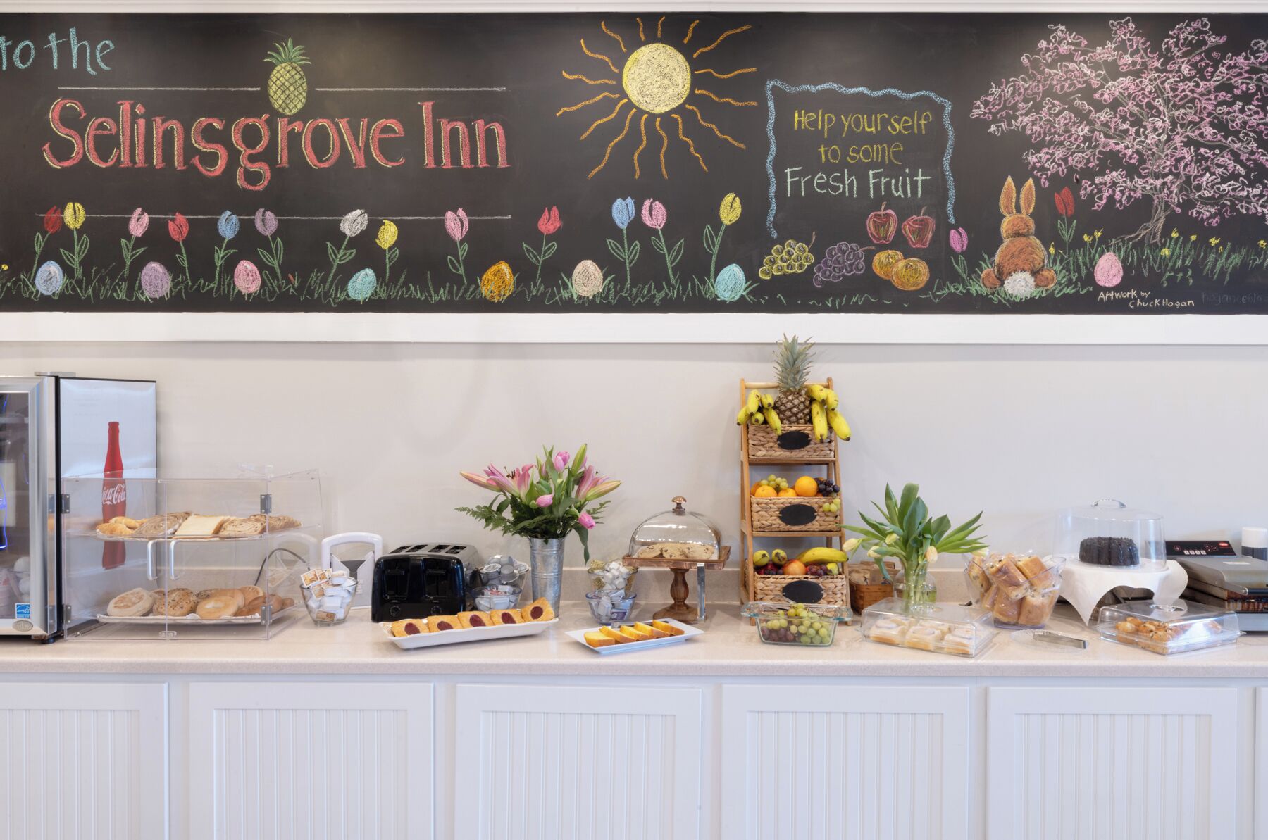 Ontbijtbuffet bij Selinsgrove Inn, met een schoolbord, verschillende soorten eten en een fruitschaal.