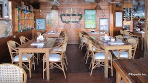 A rustic bar with wooden tables and wicker chairs, decorated with holiday wreaths and posters. - Capt'n Gregg's (Puerto Galera)