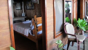 A wooden room with a bed, a chair, and a window with a view. - Capt'n Gregg's (Puerto Galera)