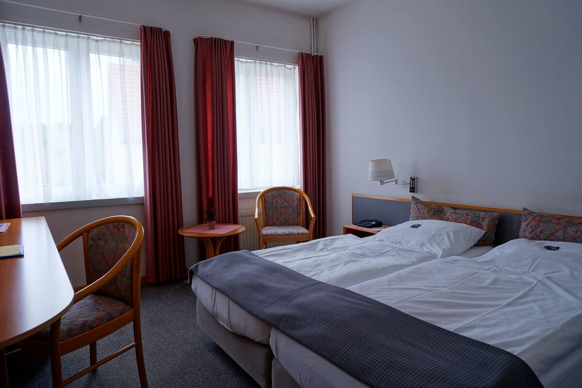 A hotel room with a bed, two chairs, a desk, and a small table.