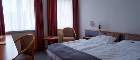 A hotel room with a bed, two chairs, a desk, and a small table.