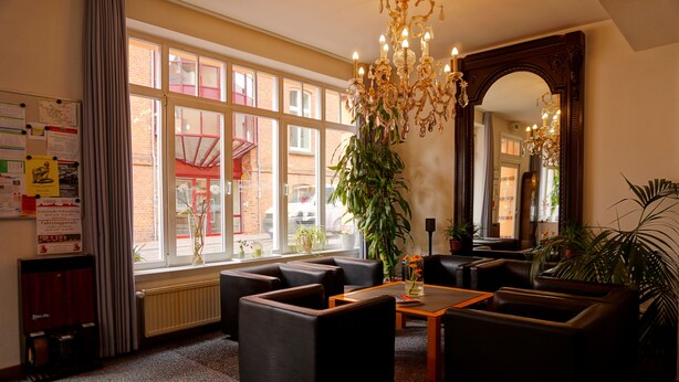 A spacious lobby with leather sofas, a wooden coffee table, and large windows offering a view of the street. - Ringhotel Altstadt (Guestrow)