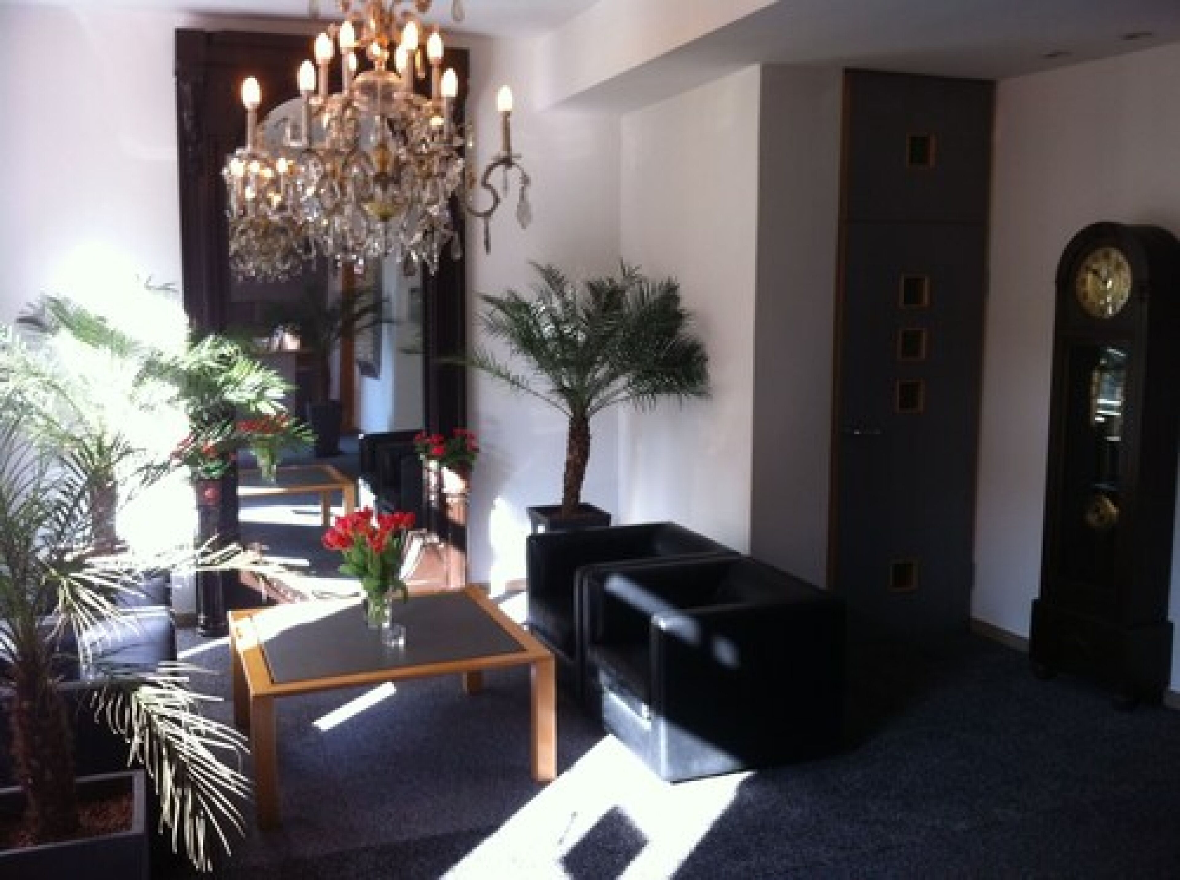 A modern living room with a chandelier, a sofa, a coffee table, and a clock on the wall.