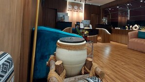 A modern lobby with a blue sofa, a large lamp, and a decorative wooden barrel. - AG Hotel (Abu Dhabi)