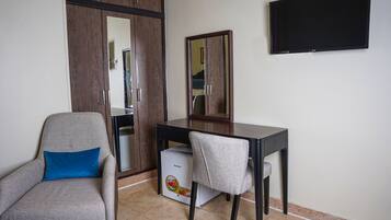 Une pièce comprenant un bureau, une chaise, une armoire et un téléviseur fixé au mur.