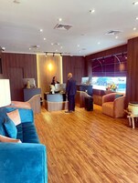 Un moderno vestíbulo de hotel con mostrador de recepción, zona de estar y un gran ventanal con vista a un automóvil.