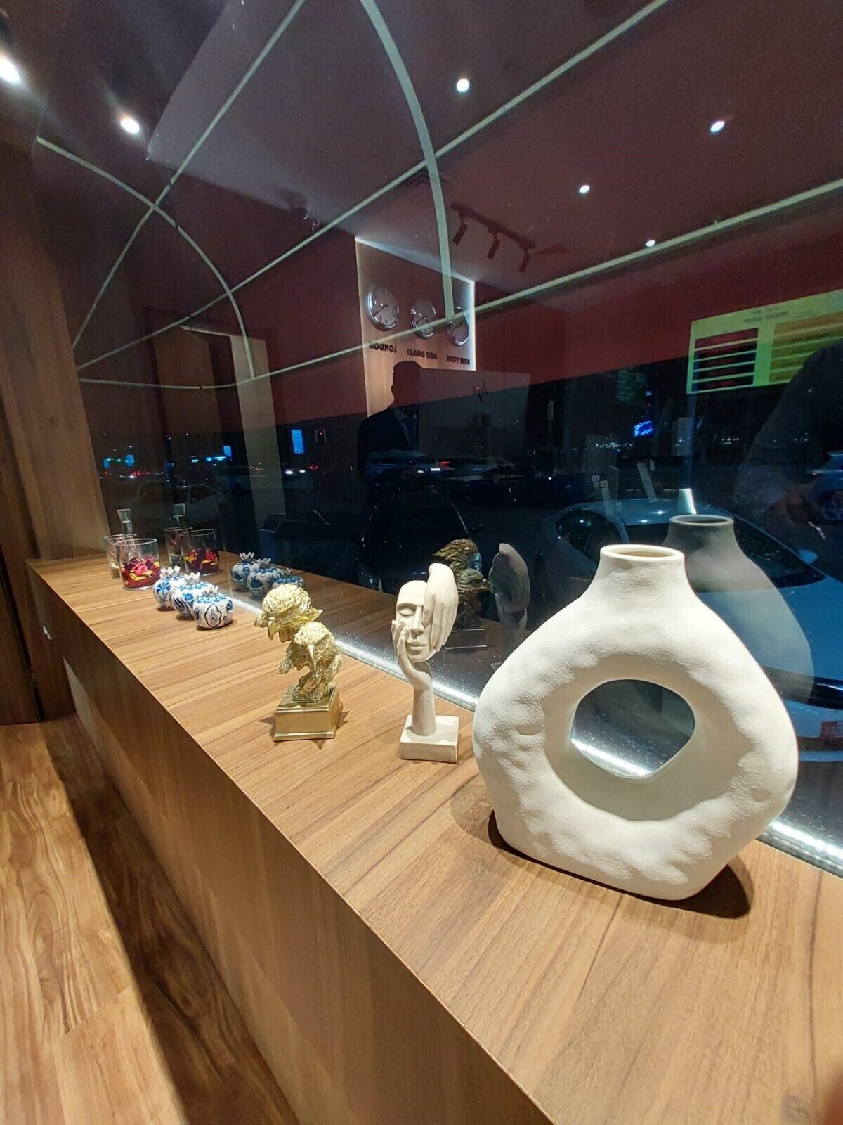 A wooden display table with various decorative items, including a vase and figurines, in a modern interior setting.