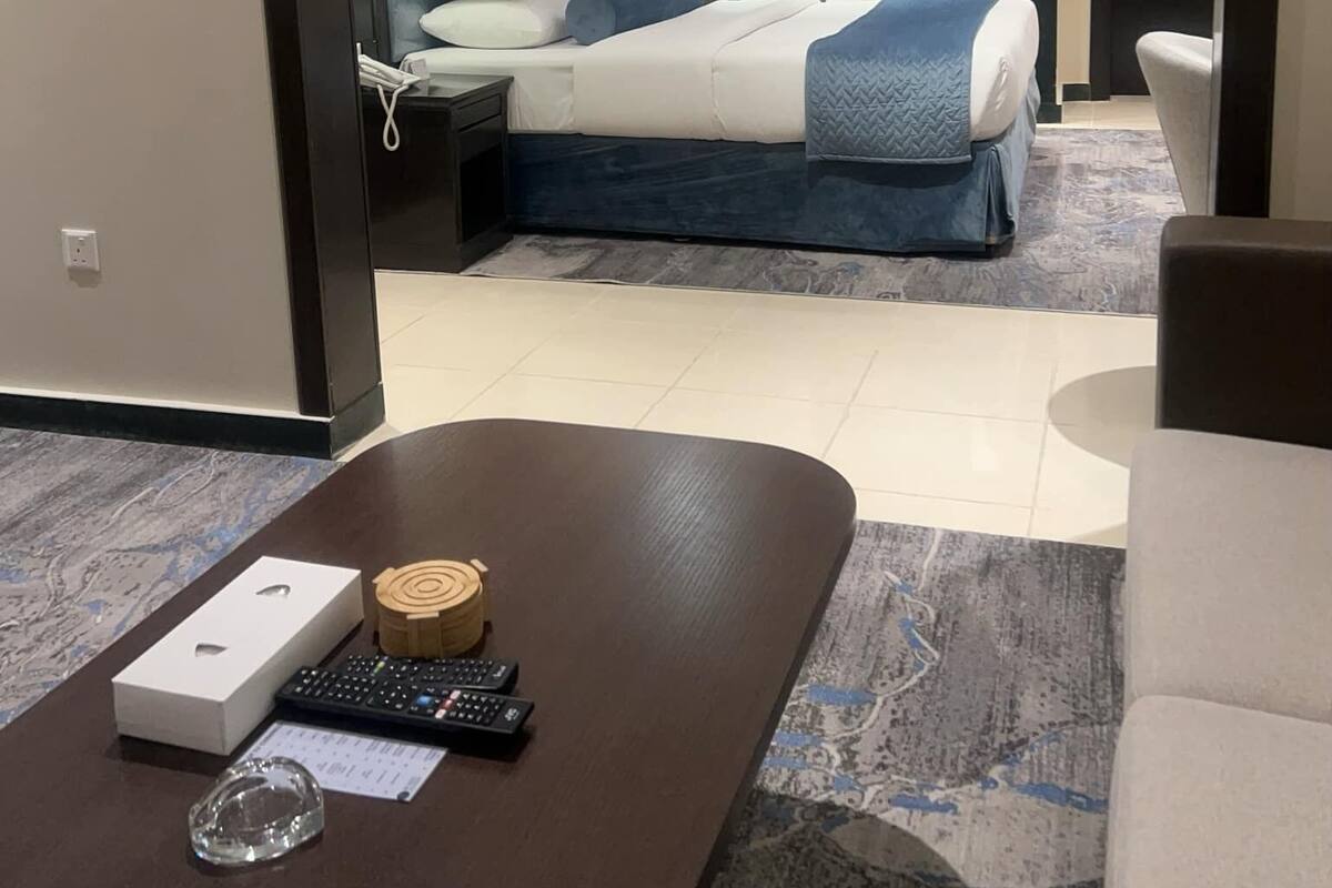 A hotel room with a bed, bedside tables, a desk with a computer, and a chair.