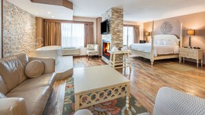 A hotel room with a stone wall, a fireplace, a bed, a sofa, a coffee table, and a TV. - Hampton Inn by Hilton Sydney (Sydney)