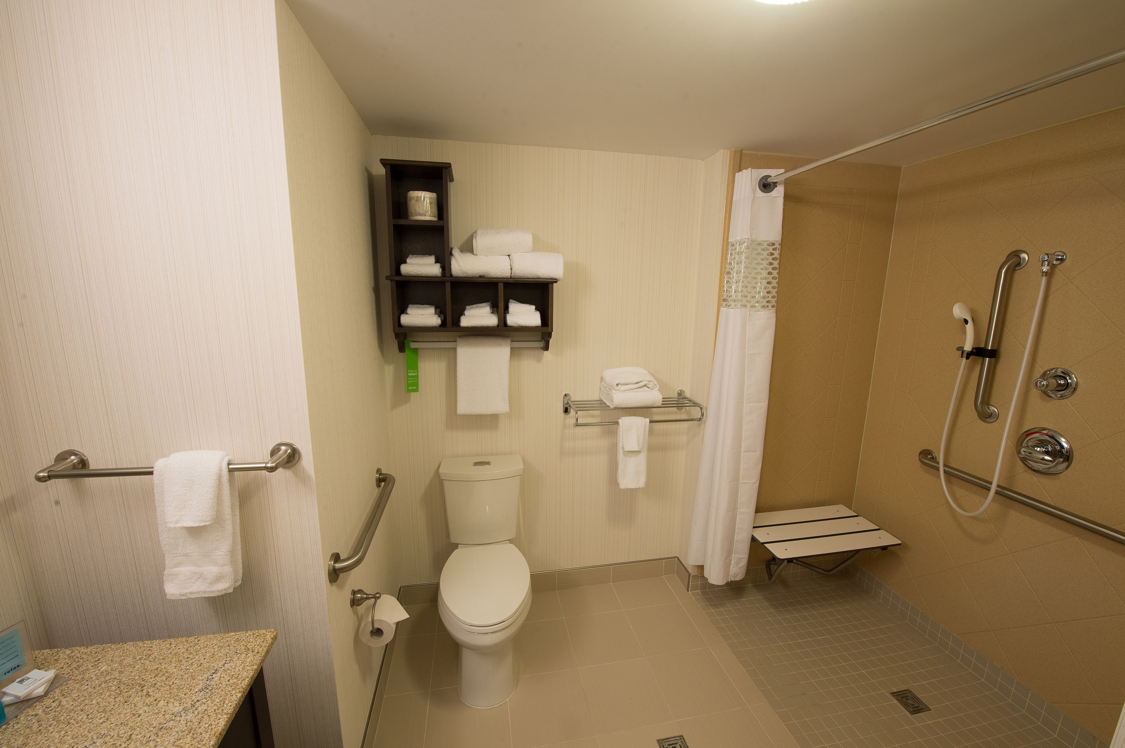 A standard hotel bathroom with a toilet, sink, shower, and towel rack.