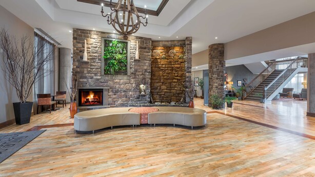 A spacious living area with a stone fireplace, a large chandelier, and a curved seating arrangement. - Hampton Inn by Hilton Sydney (Sydney)