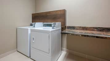 A laundry area with two stacked washers and dryers, a wooden headboard, and a marble countertop.