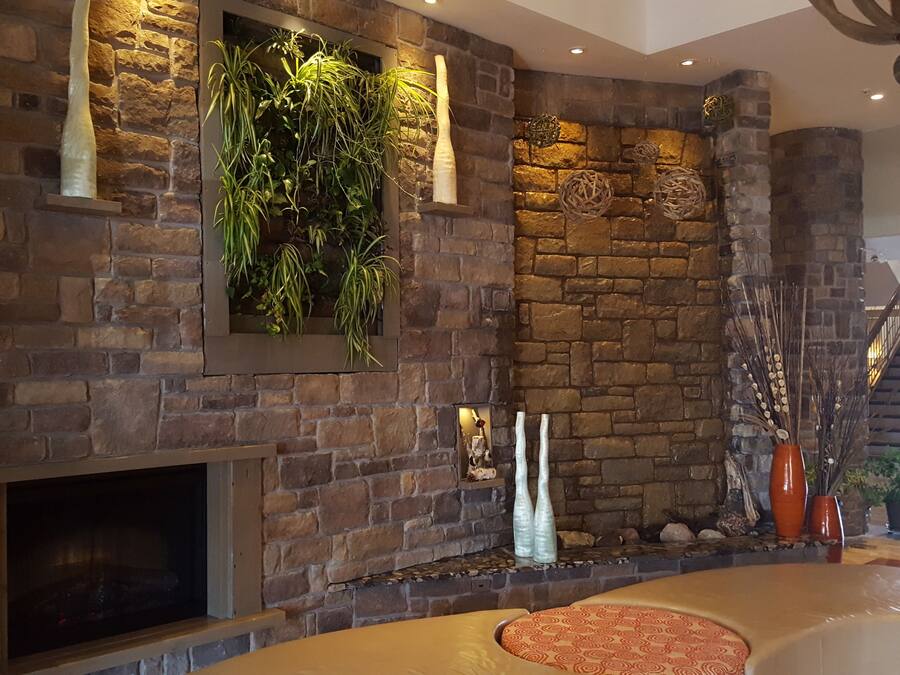 A stone fireplace with a built-in planter, a seating area with a patterned cushion, and a staircase leading to an upper level.