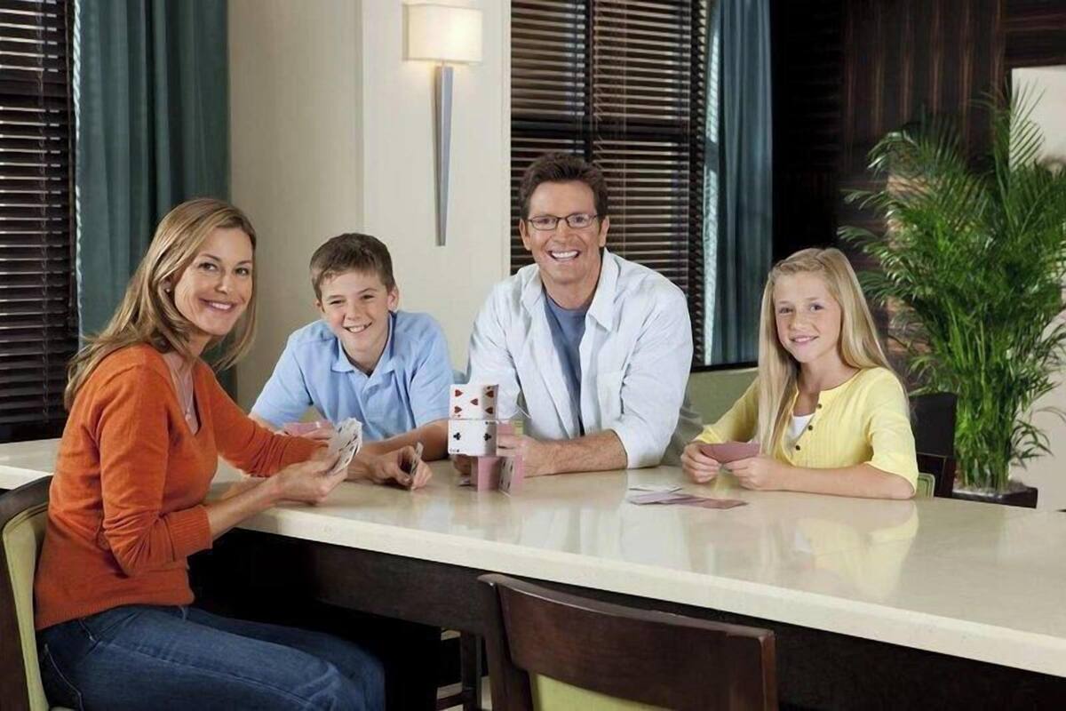 A reception desk with a family seated, a plant, and a window with blinds.