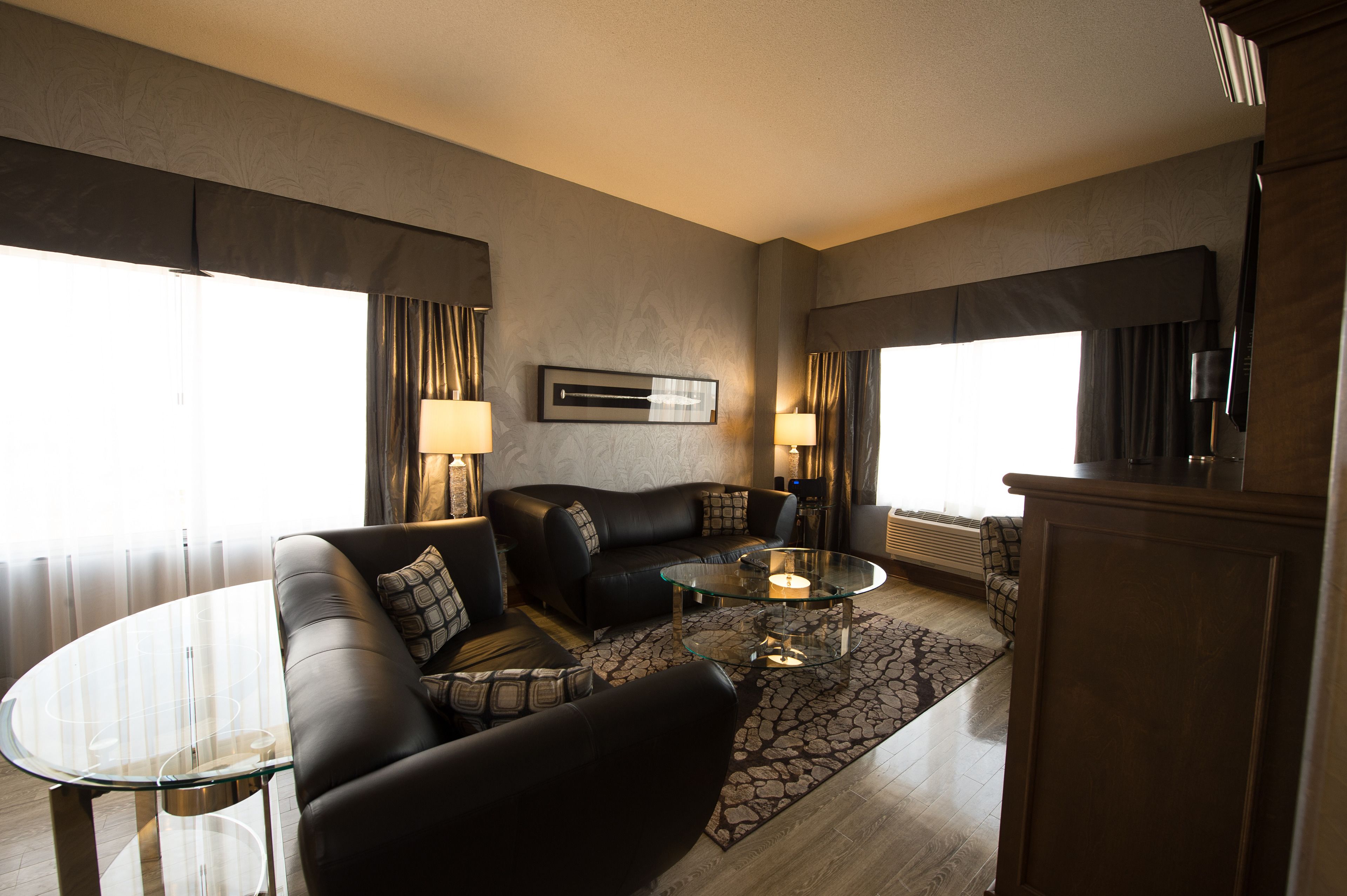 A modern living room with a leather sofa, glass coffee table, and a patterned rug.