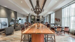 A spacious dining area with a long wooden table, surrounded by chairs, and a large chandelier. - Hampton Inn by Hilton Sydney (Sydney)