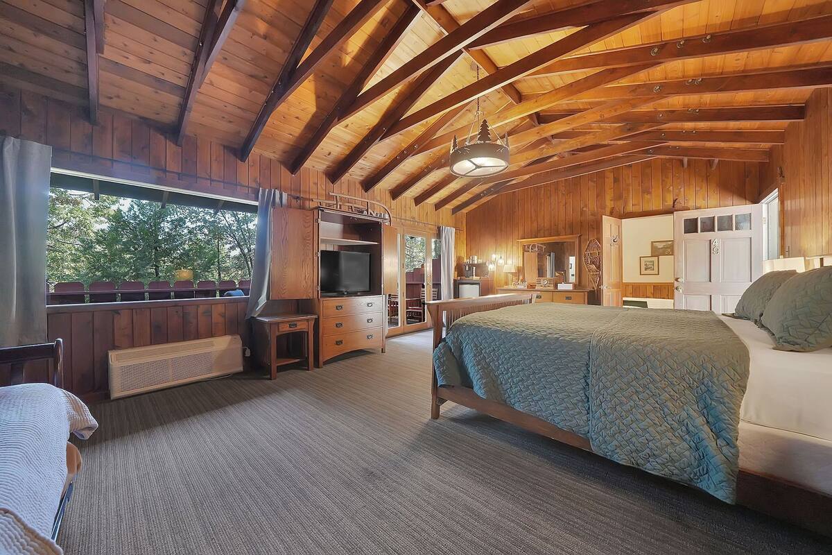 A wooden cabin with a large bed, a TV, and a cozy seating area.