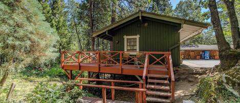 A rustic cabin with a wooden deck and a small porch.