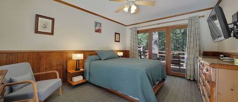 A bedroom with a bed, a chair, a nightstand, a dresser, a ceiling fan, and a window with a view of the outdoors.