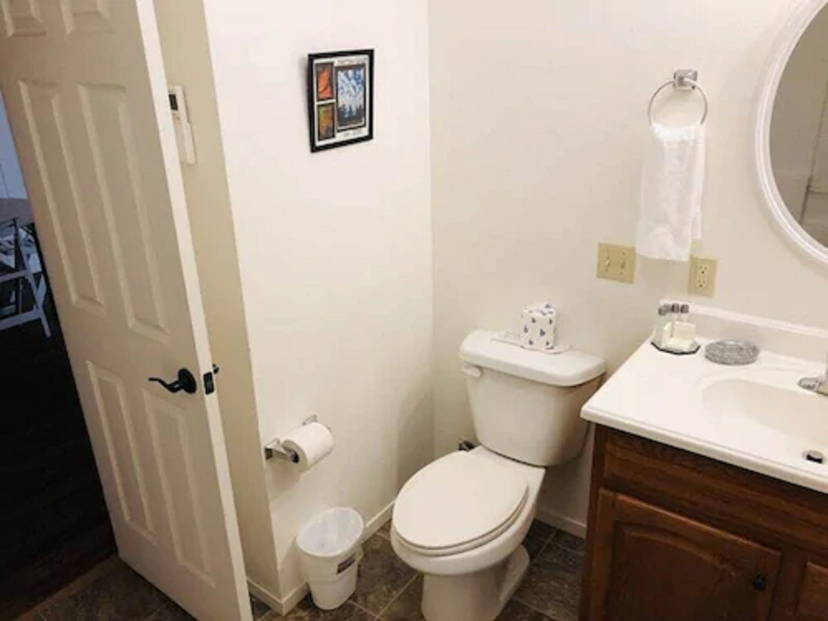 A bathroom with a toilet, sink, and a small trash bin.