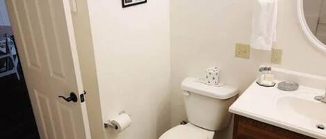 A bathroom with a toilet, sink, and a small trash bin.