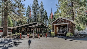 Eine rustikale Lodge mit einer Veranda, einem Oldtimer und amerikanischen Flaggen.