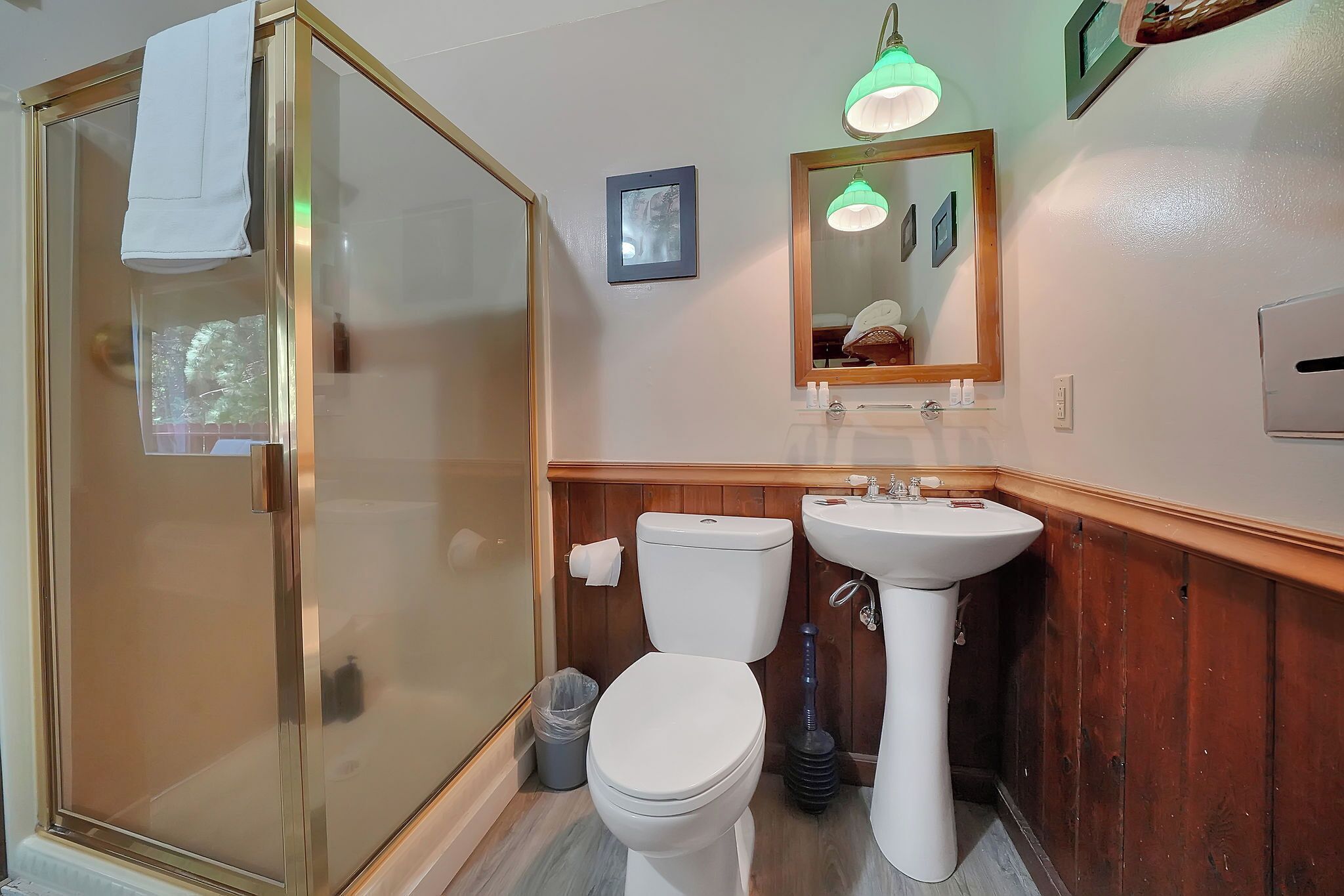 Une salle de bain avec une douche à parois de verre, des toilettes, un lavabo et un miroir.