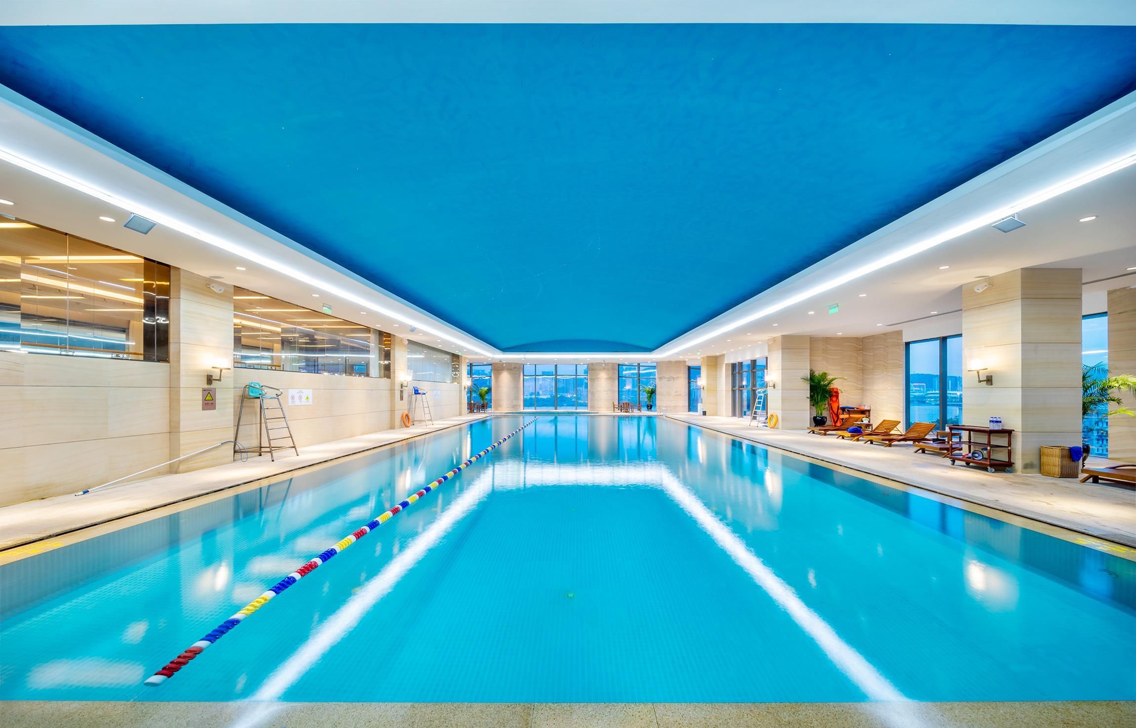 Una piscina interior con carriles delimitados, techo azul e iluminación moderna.