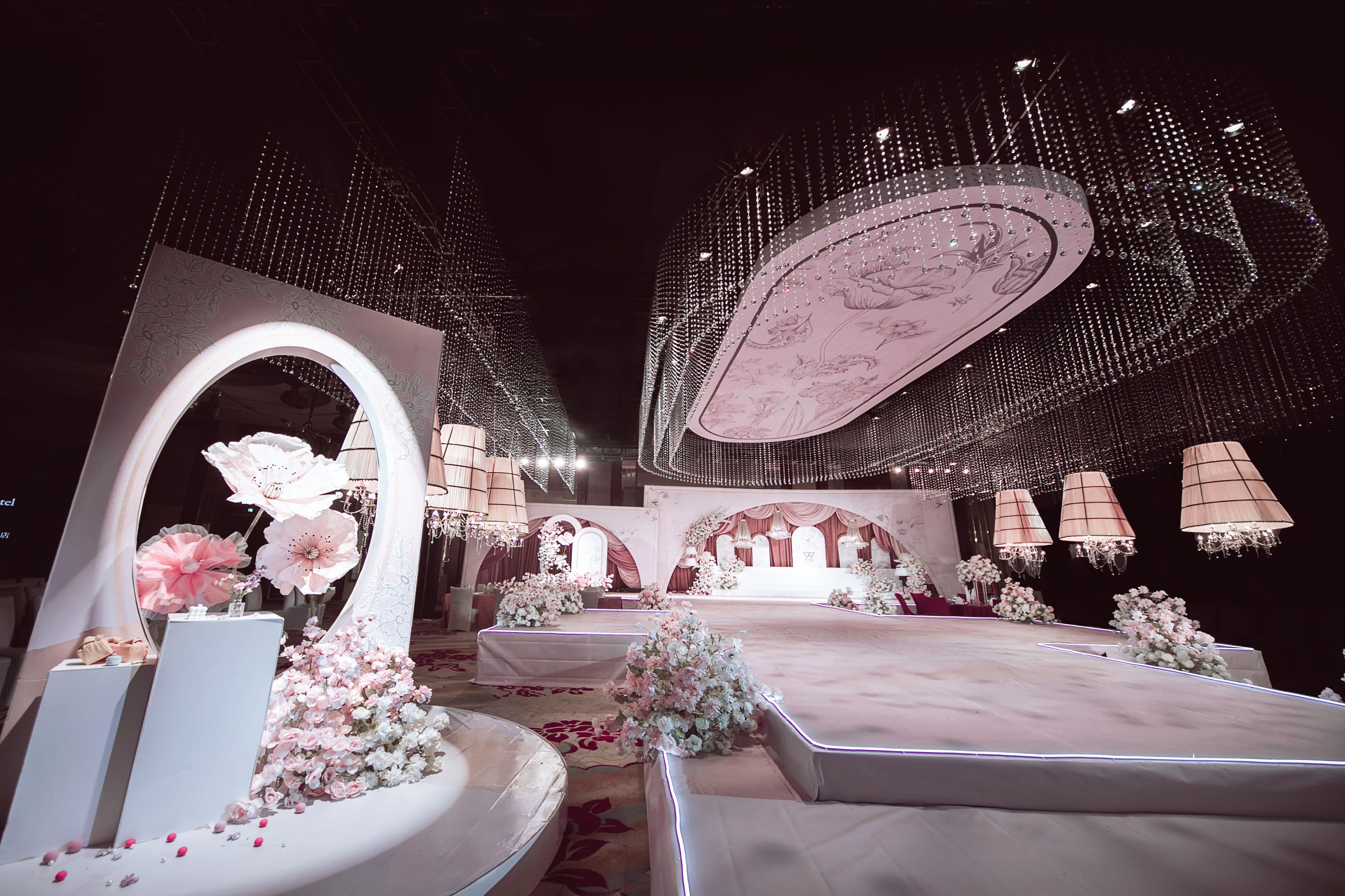 A stage with a floral arrangement, a large mirror, and a chandelier.