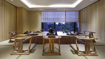 A traditional Japanese-style dining room with a low table set for six, surrounded by wooden chairs.