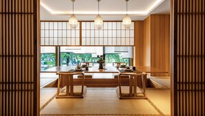 Una habitación tradicional japonesa con suelo de tatami, una mesa de madera baja y vistas a zonas verdes.