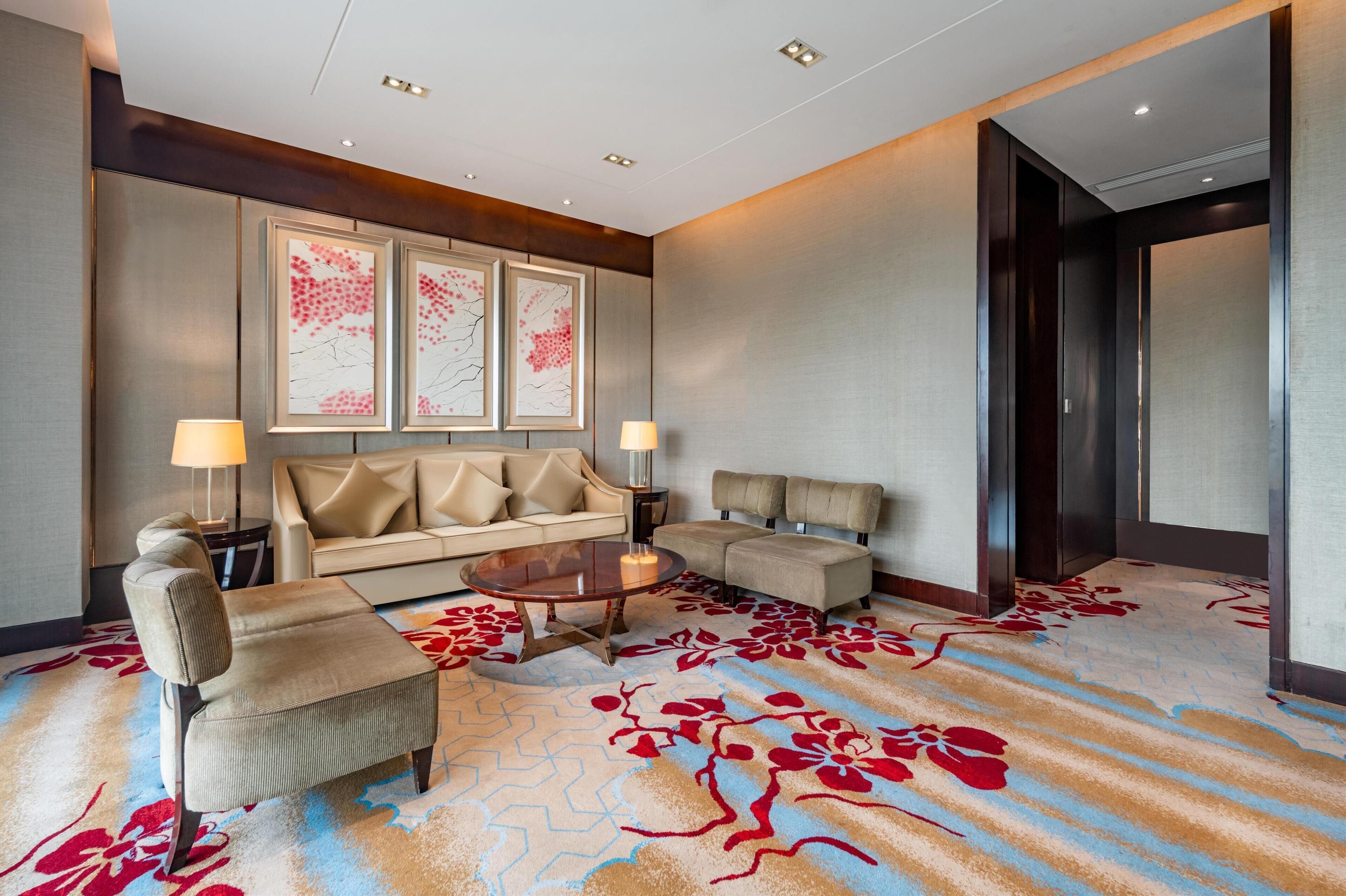 A hotel lobby with a sofa, armchairs, a coffee table, and artwork on the wall.