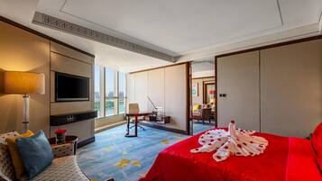 A hotel room with a large bed, a TV, a desk, and a view of the city.